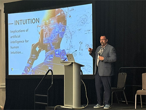 A man stands before a presentation screen.