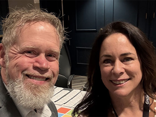 A man and woman smiling together for a photo at a professional conference.