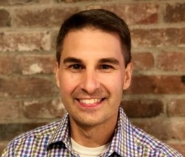 a man standing in front of a brick wall posing for the camera