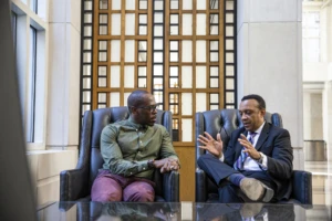 Two people sitting down talking to each other in a bright office setting.