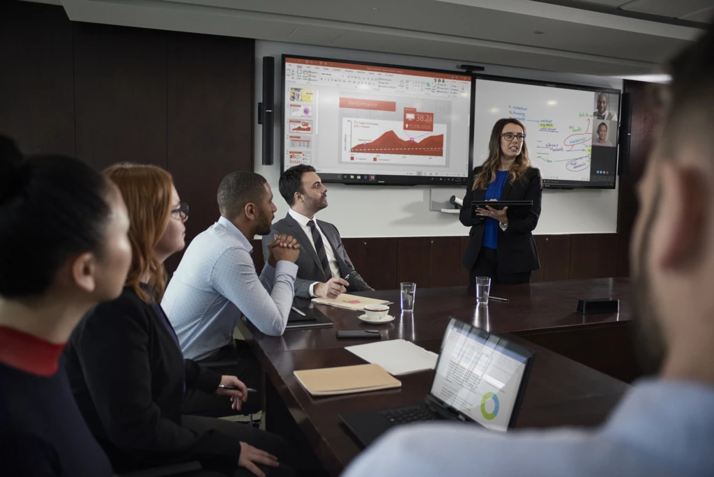 A group of people sitting in a meeting reviewing performance data.