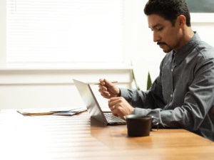 A man sitting at a table using a laptop