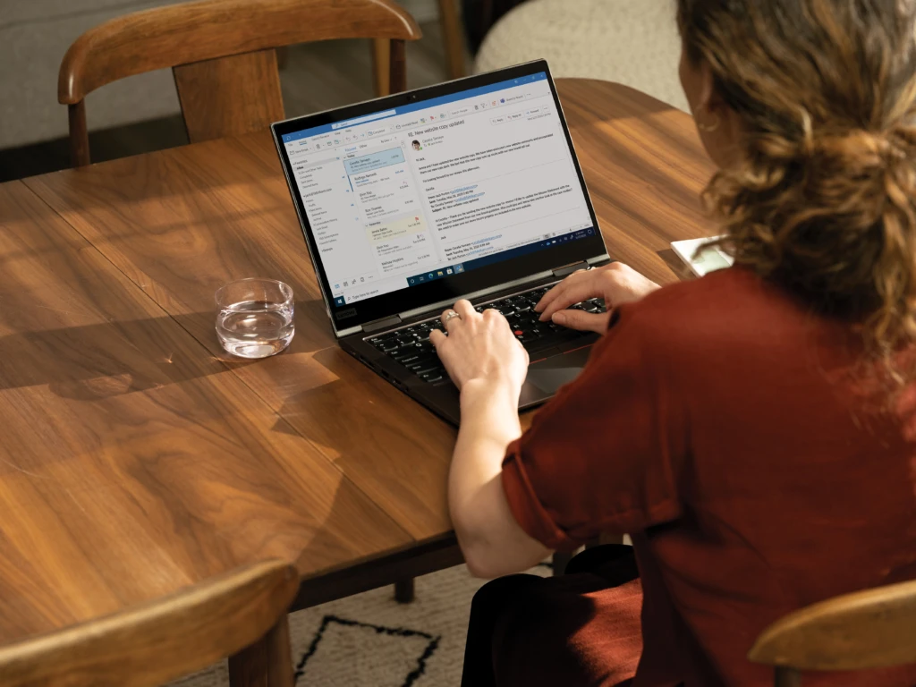 Over the shoulder photo at a dining room table with a Lenovo ThinkPad X1 Yoga. Remote Working collection. Keywords: remote work, remote working, work from home, working at home, home office