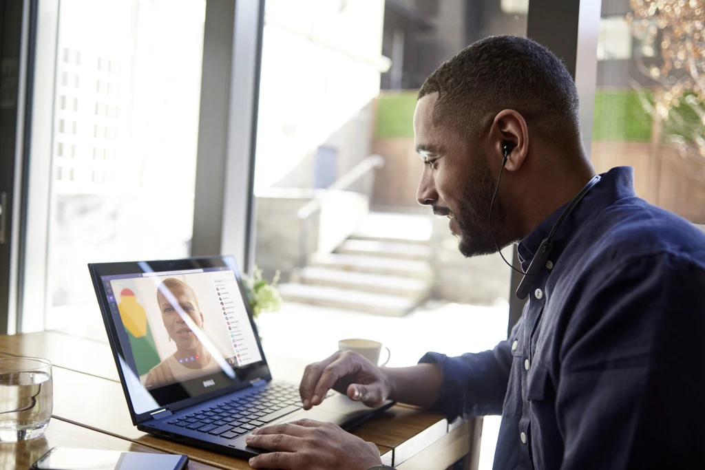 Male business professional at table using a Dell 3390 device that is running Microsoft Teams.