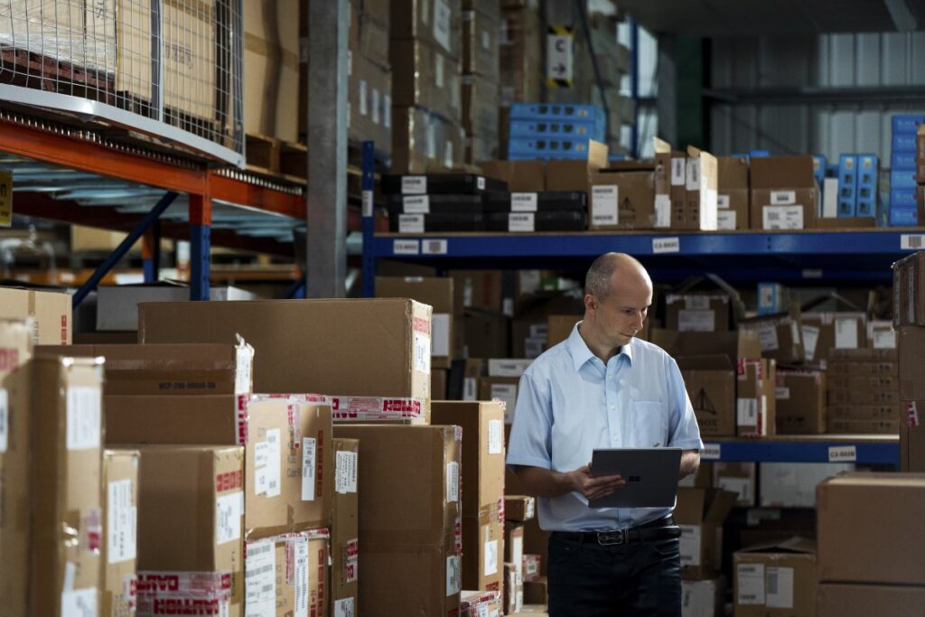 A Firstline Worker in a warehouse using a Surface device as a tablet to make notes.