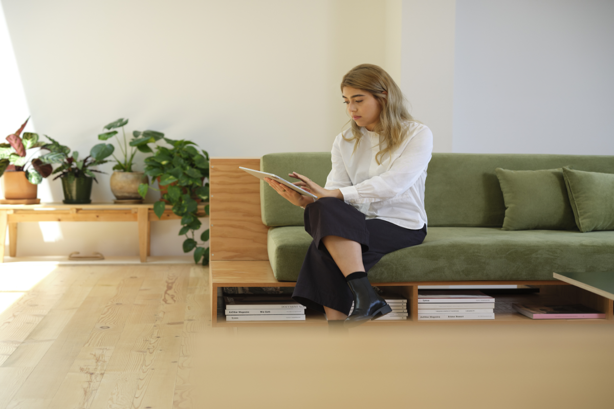 A female architect sitting on a green couch using a Surface tablet.