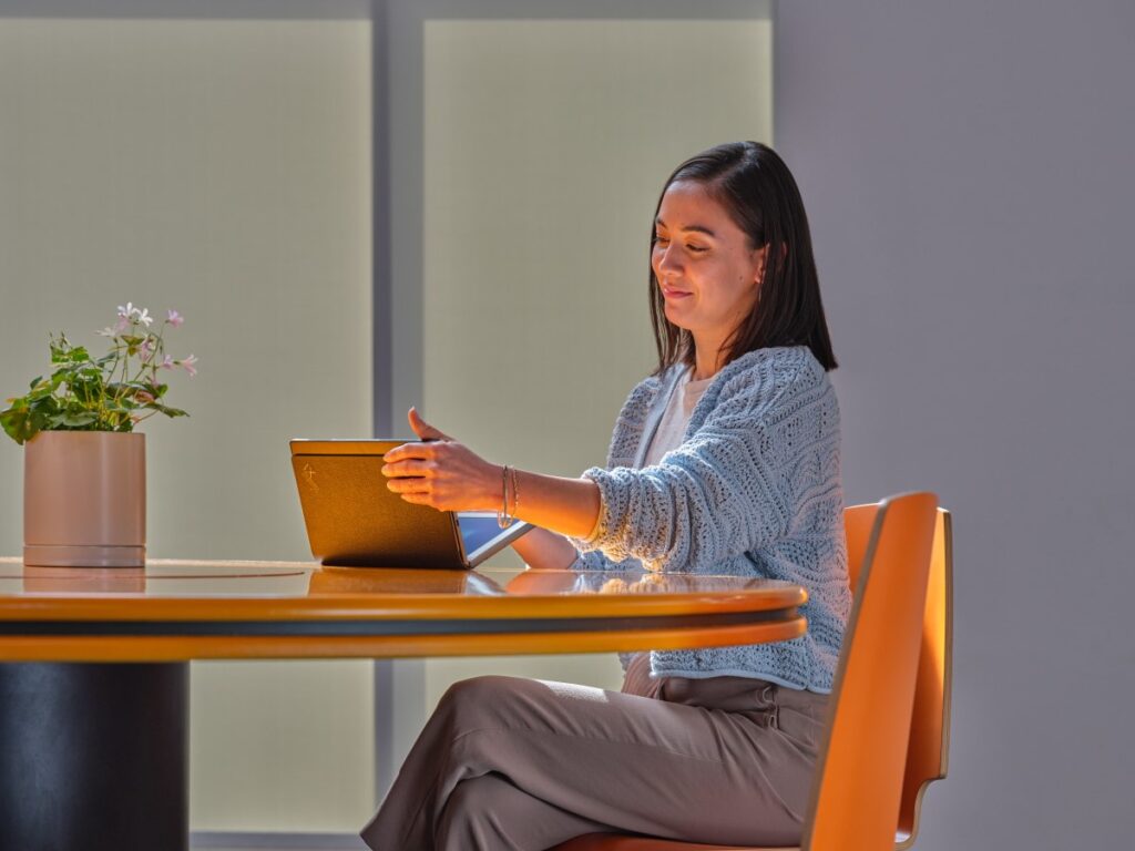 Business person closing Lenovo ThinkPad X1 Fold while sitting at a conference room table.