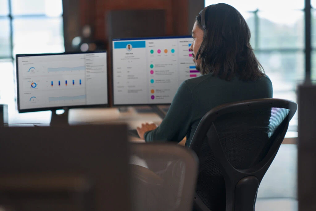 An agent looking at two monitors during a customer service call.