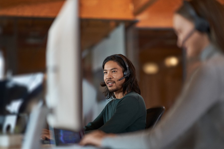 Man sitting at a computer with a headset on.