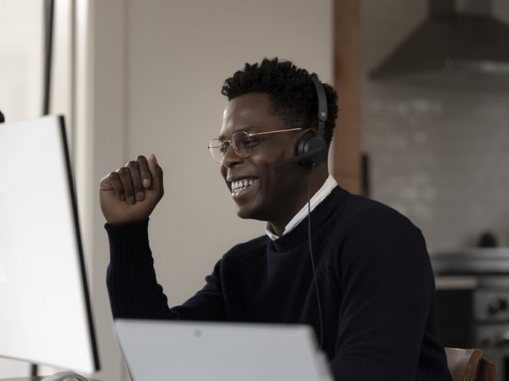 Adult male sitting at office desk, smiling with headset on.