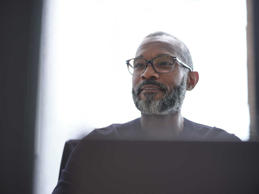 Man with glasses, seated, looking ahead.