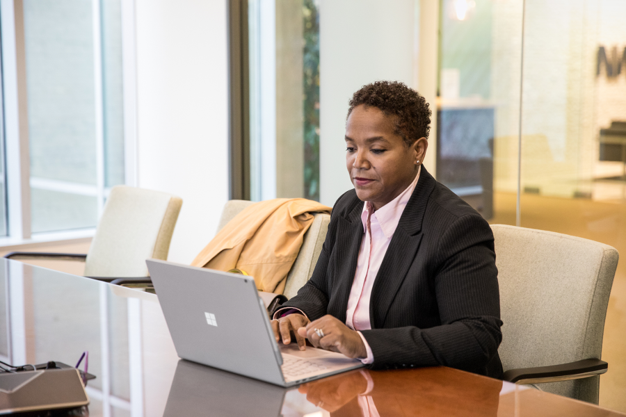 Kendall Clawson in a suit sitting at a table using a laptop