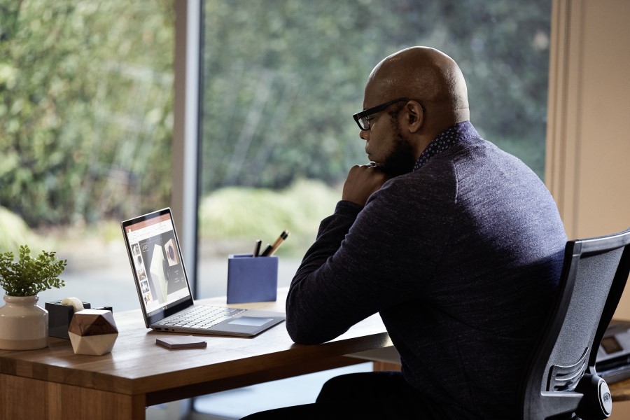 Male working remotely from his home office on a Dell Latitude 13 device, running Microsoft PowerPoint.