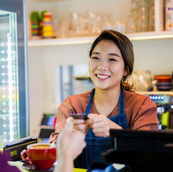 Woman working in a café receiving credit card payment from her customer.