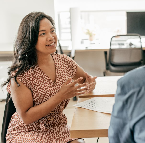 A person sitting at a desk talking to another person