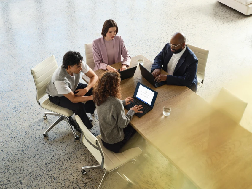 A group of people sitting at a long table, using laptops to evaluate a product and outcome