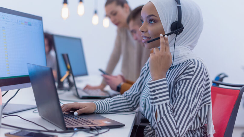 Female Customer Service Representative Answer Client's Questions in a Headset. Multi-Ethnic Team of Specialists.
