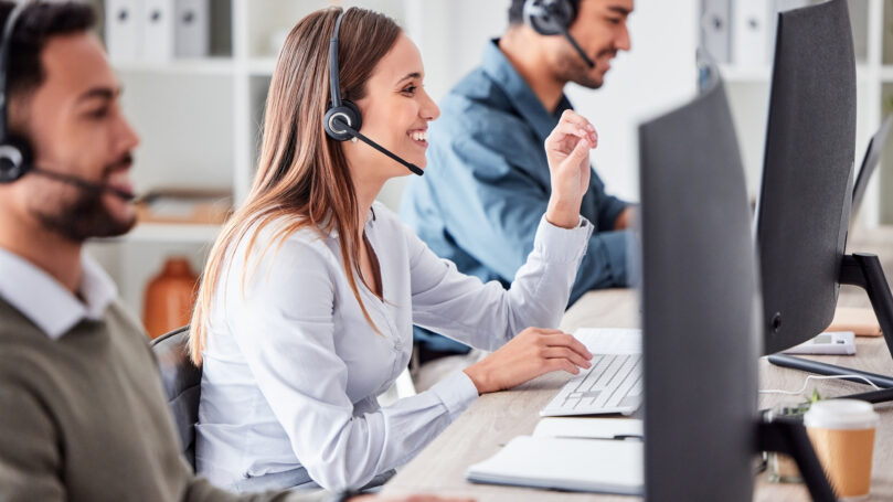 Call center, woman and working in team office with headset, computer and online customer support, service or help. Businesswoman, smile and contact us, crm and telemarketing employee talking.
