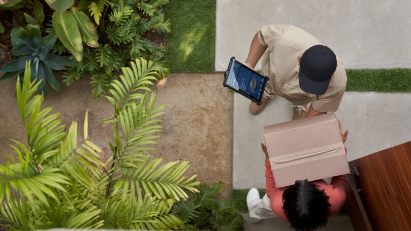 A delivery driver hands a package to a resident at their front door.