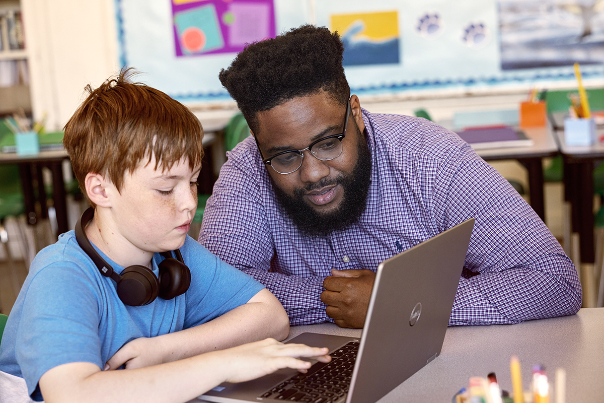 A educator talking to a student in a school classroom.