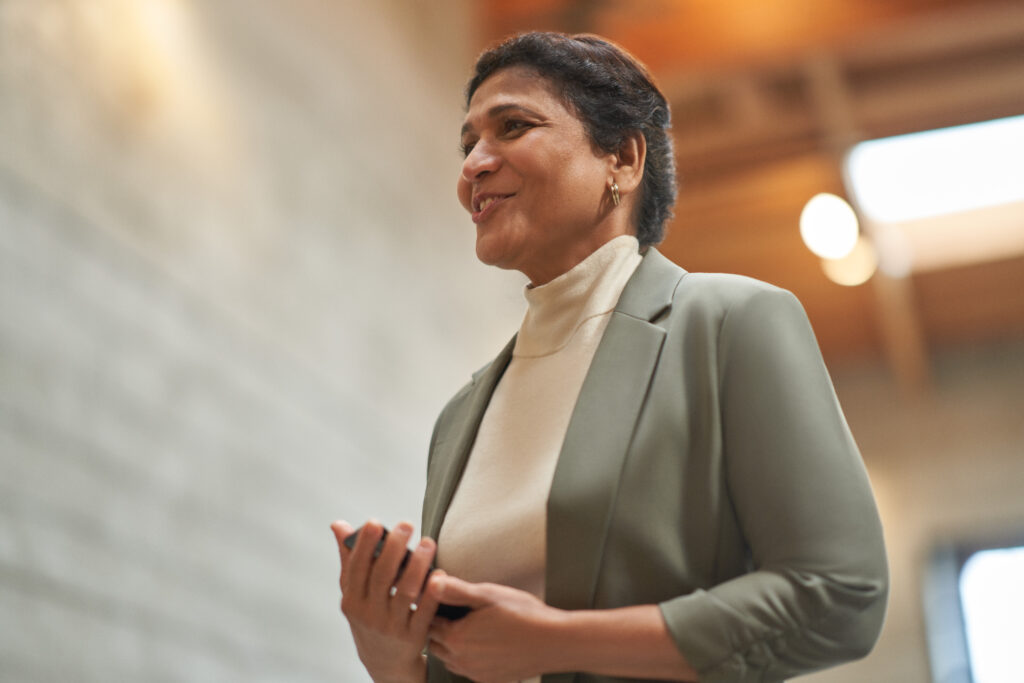 A person standing and holding a cell phone. 