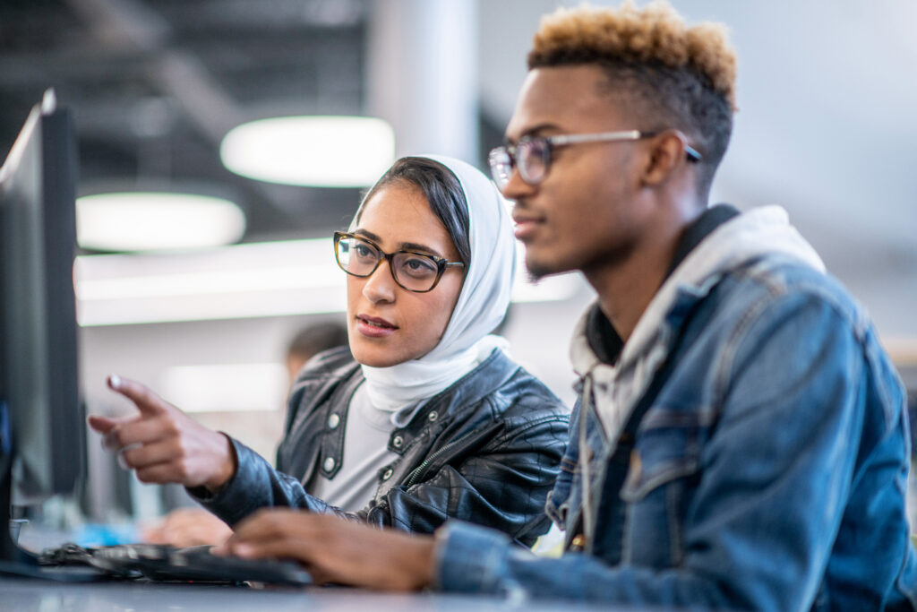 Two university students working together on a computer. 