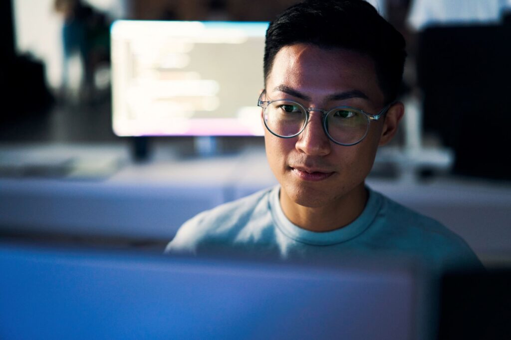 A person sitting at a desk and looking at a computer screen.