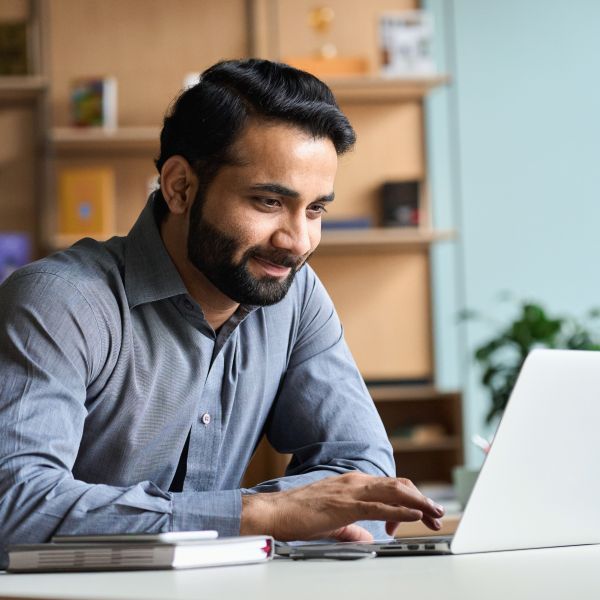 An education professional works on a laptop in a school office.