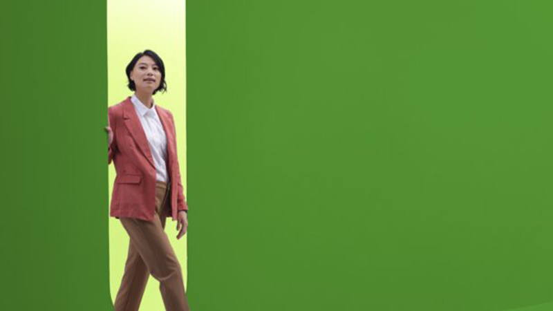 business woman walks through an opening between 2 green wall panels