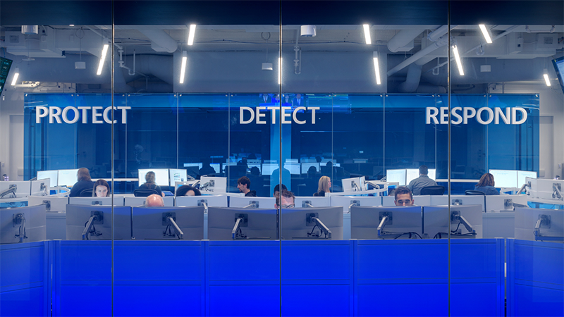security team working at computer monitors with the words “protect,” “detect” and “respond” on the wall