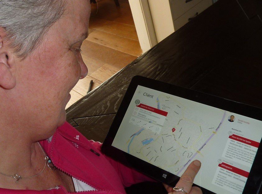 An older woman interacting with WinCare solution on a Microsoft tablet