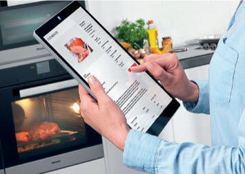 Person using a tablet in front of an oven