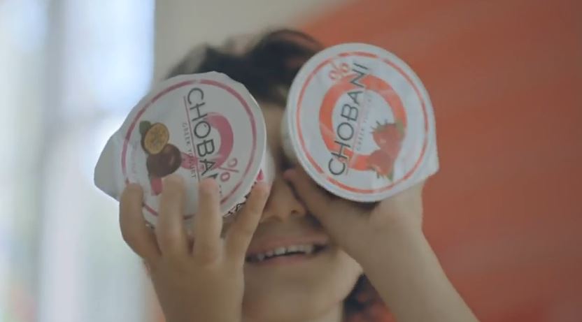 A kid holding two chobani yogurt containers