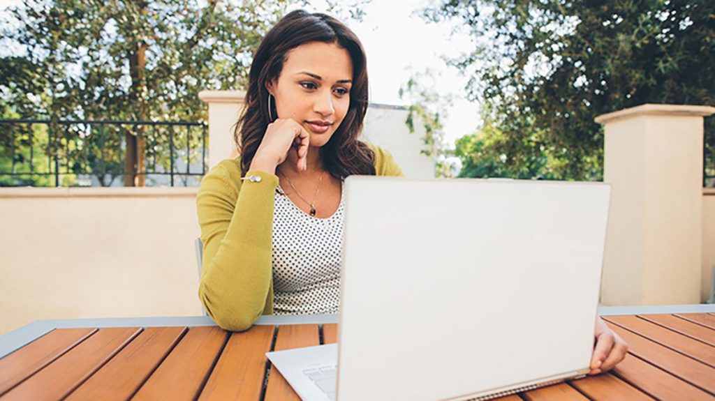 woman sitting outside with a laptop on a table