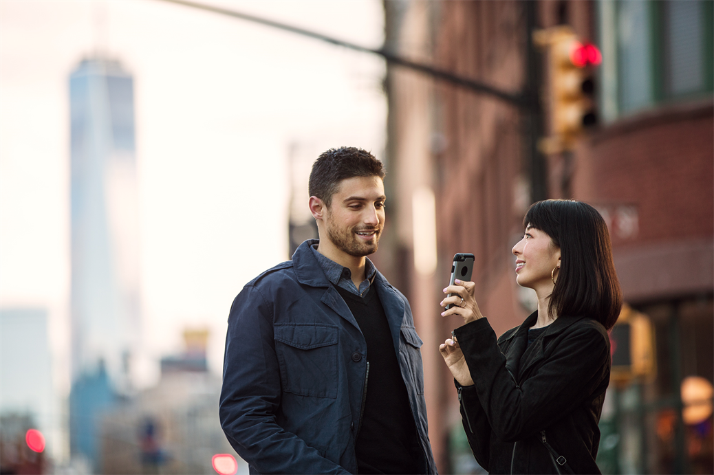 Man and woman standing in street looking at a phone