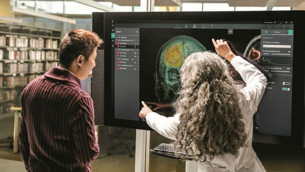 A man and a woman in a library looking at a brain scan.