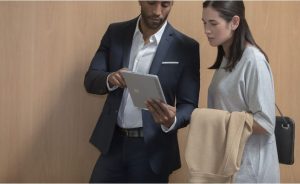 Man showing a woman something on a surface book.