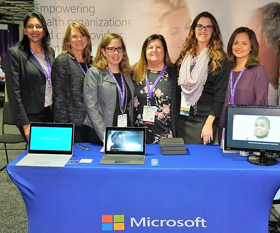 Six women standing behind a Microsoft table at a conference