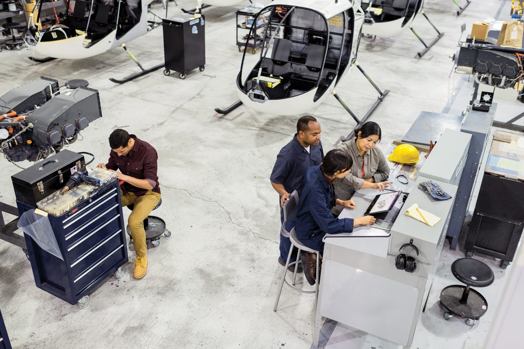 Four employees working with tools in a helicopter factory