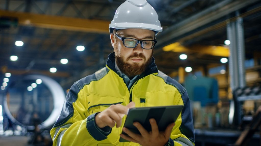 Factory employee in hardhat holding tablet
