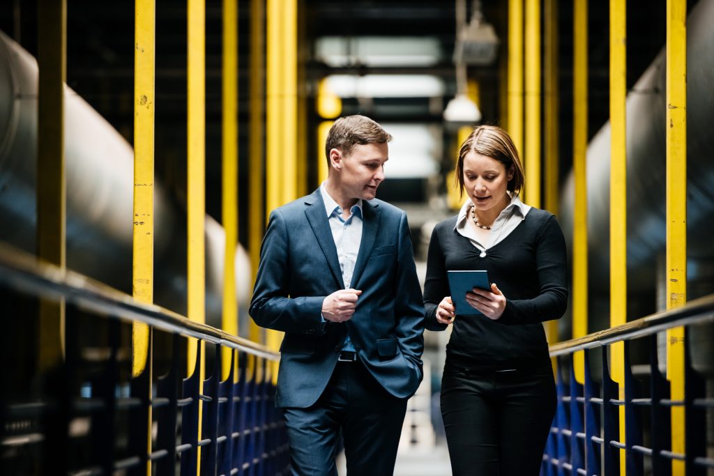 Two Business Person Walking A Dark Factory Hallway