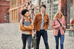 Three people with devices walking in city