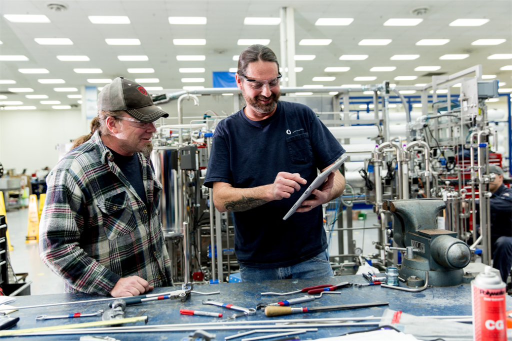 Two men working in factory while looking at device