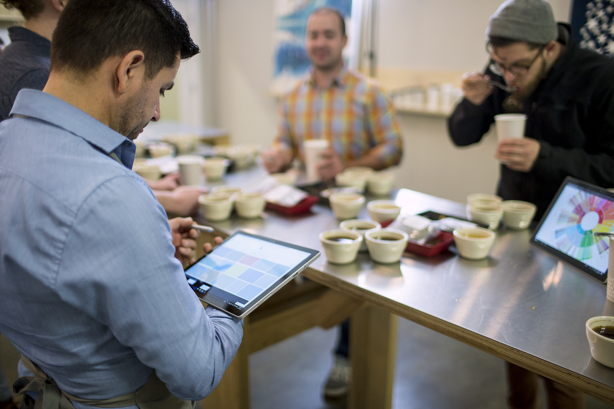 Customers tasting coffee while employee collects data from them