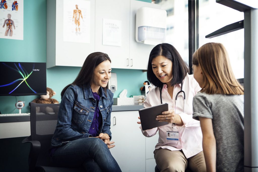 Doctor talking with patient while looking at information on a device