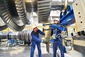 Workers assembling and constructing gas turbines in a modern industrial factory