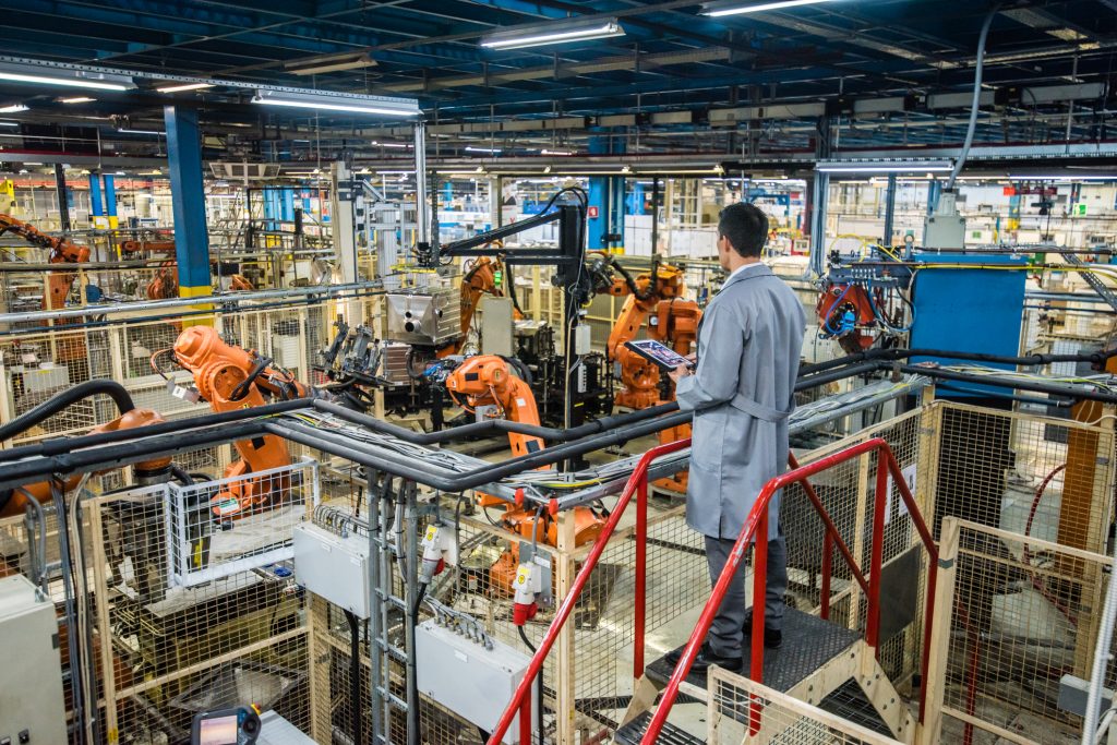 Factory engineer inspecting the work process of the robots performing their operations in appliance manufacturing factory.