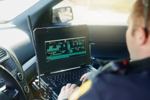 Police officer in a patrol car working on a computer
