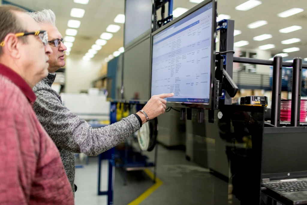 Two people looking at a large computer screen in a modern factory