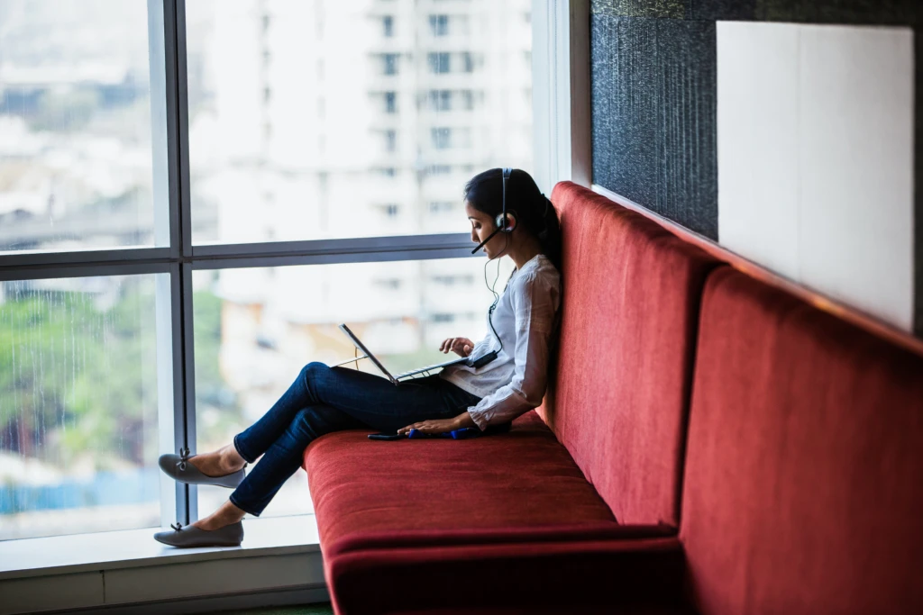woman sitting and looking at a laptop wearing headphones